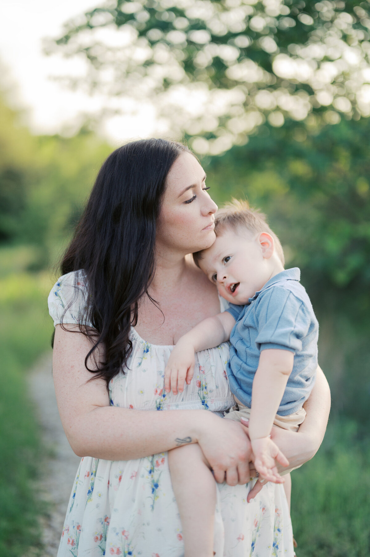 mom snuggles son close as he rests on her pregnant belly