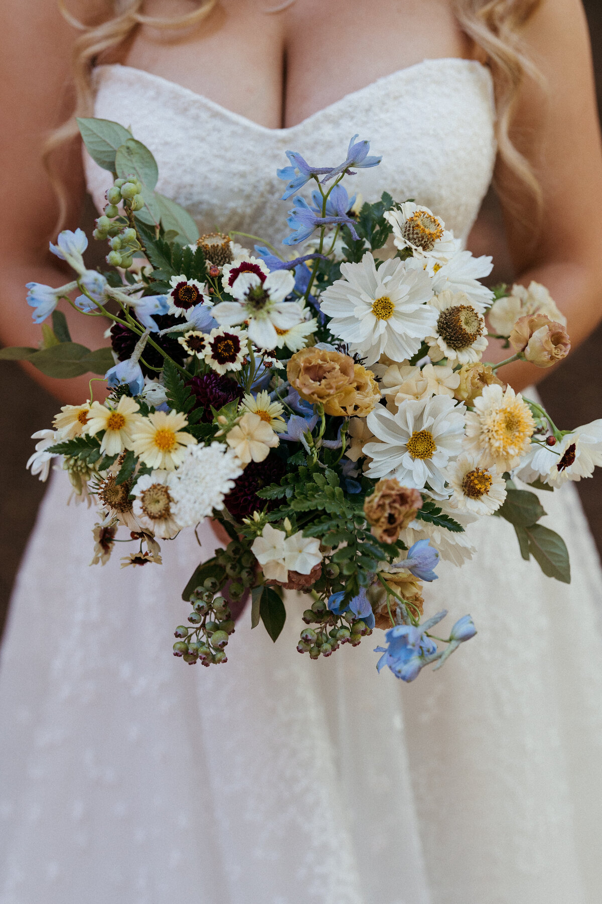 Whimsical wildflower bridal bouquet with shades of white, gold, plum, and blue