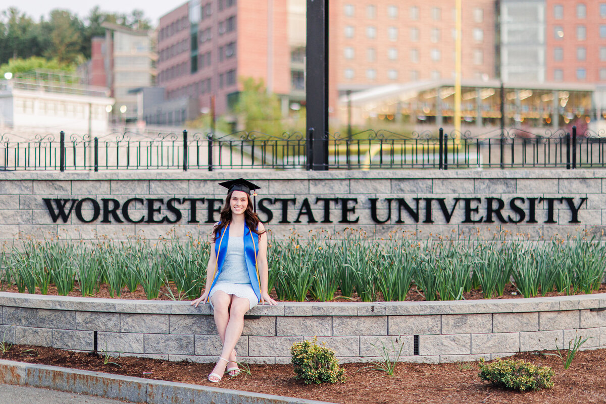 Girl sitting in front of university sign representing Boston senior photos