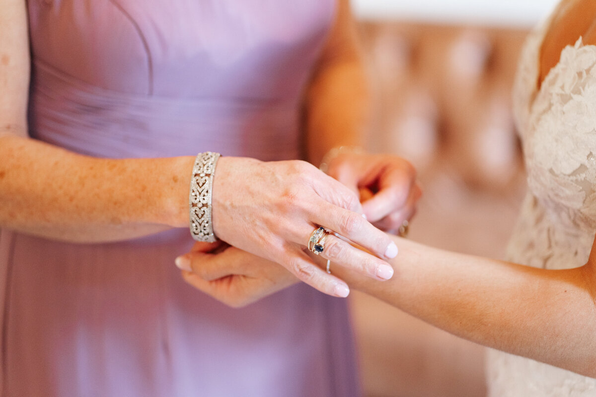 Bride putting on earrings in soft window light before her New England wedding