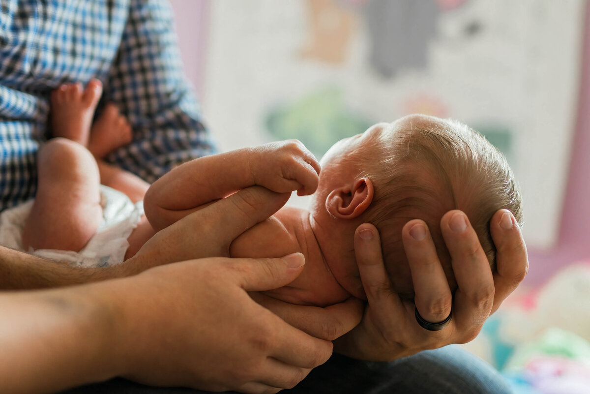 Baby in diaper being held in Dad's hands