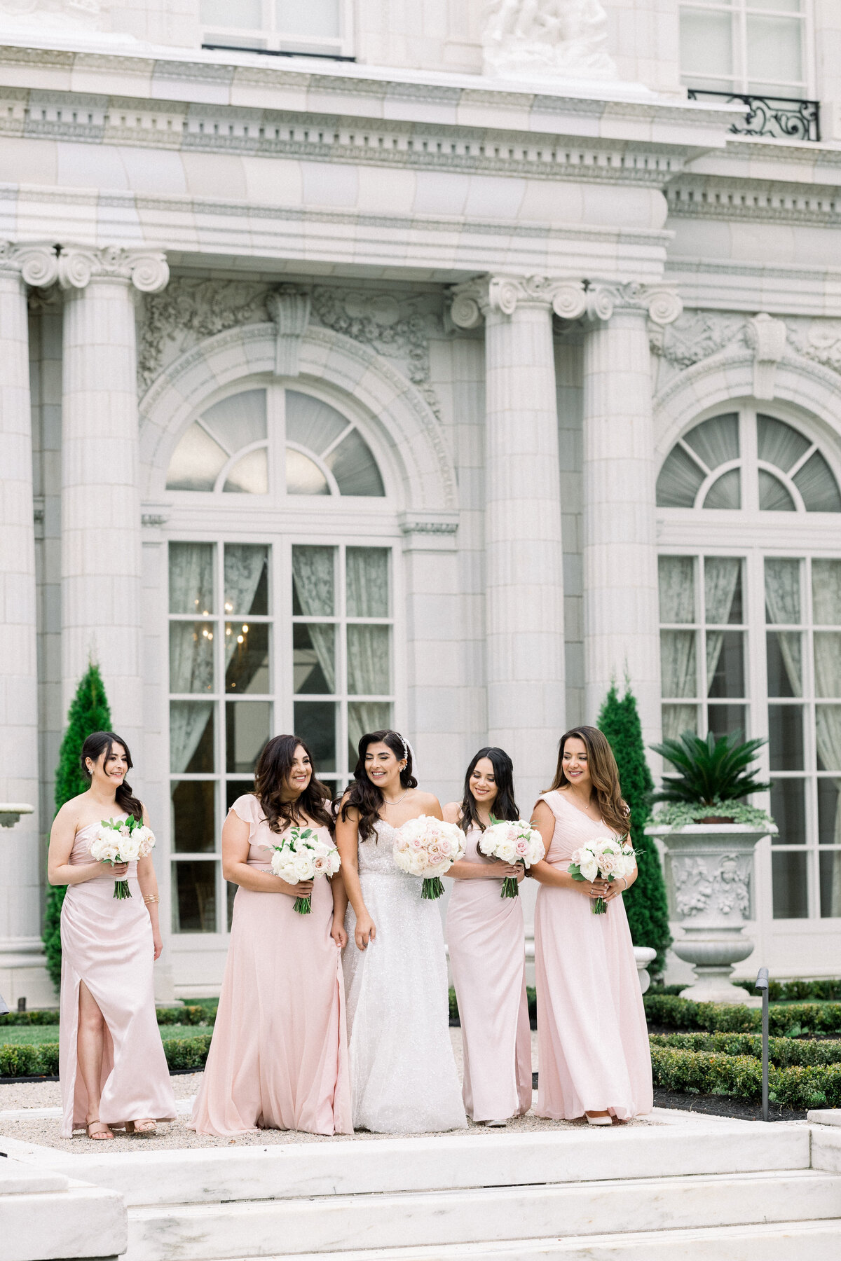 bridesmaids walk down the stairs for candid portraits in front of rosecliff mansion
