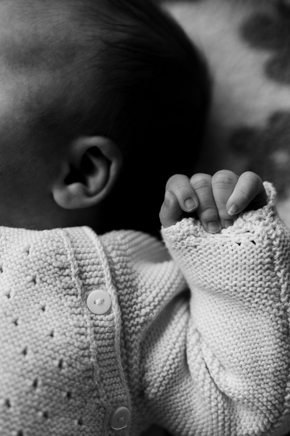 Zwart-witfoto van een babyhand die zachtjes een vinger vasthoudt, symboliserend tederheid en onschuld.