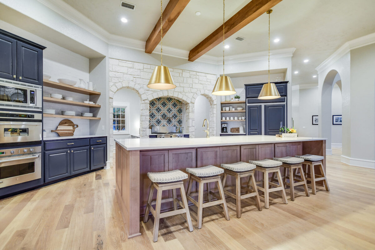 blue kitchen with large kitchen table and gold hanging lampshades above island