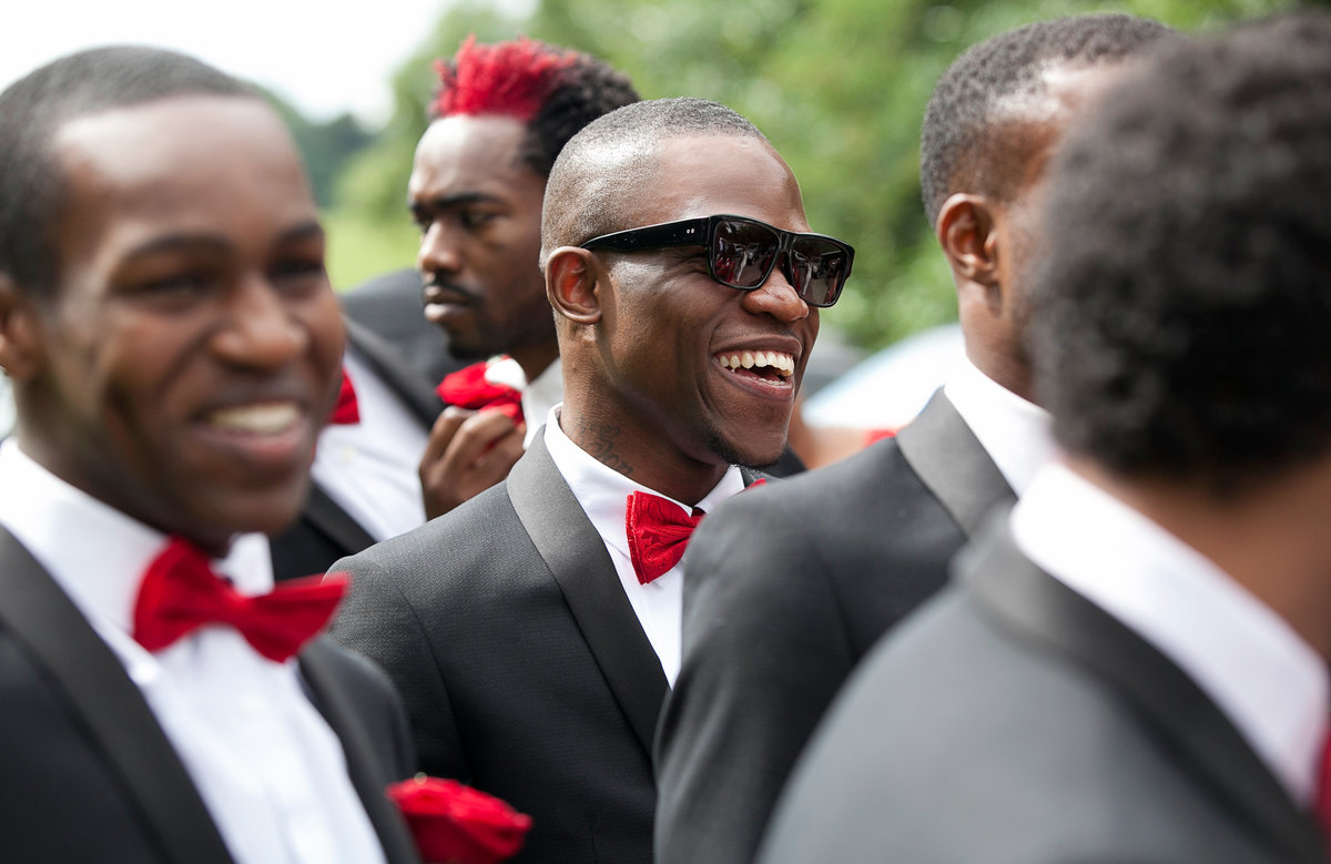 Candid natural photo of these stylish groomsmen in black suit with red bow tie at this nigerian wedding in London