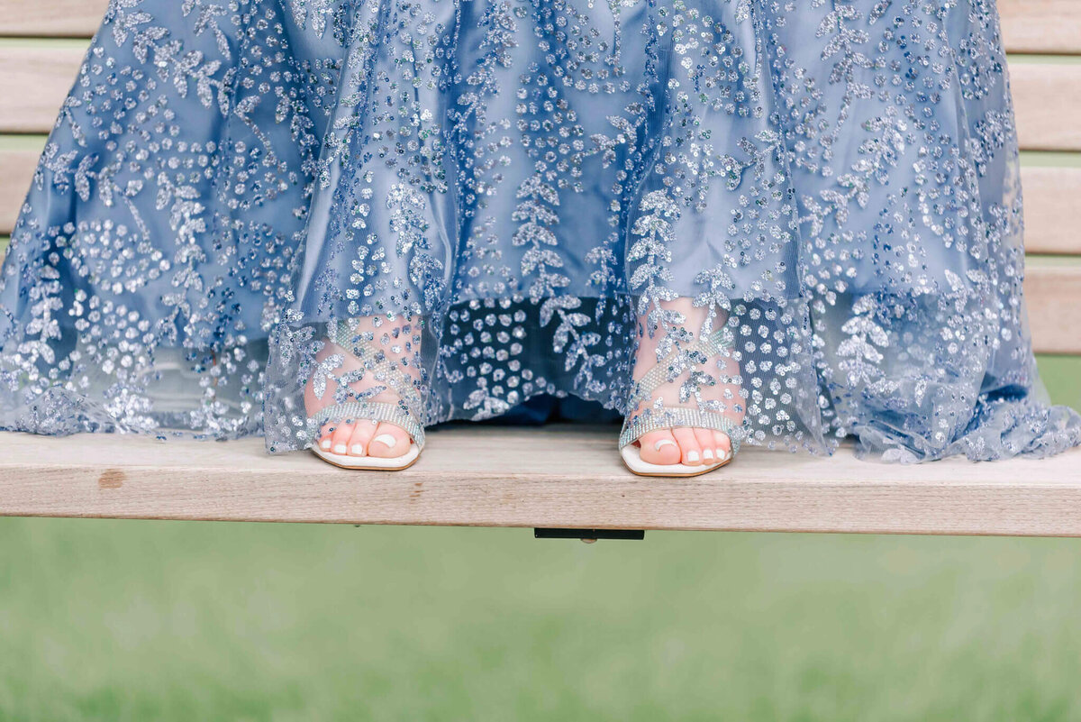 Sitting on a bench showing off her shoes. 
