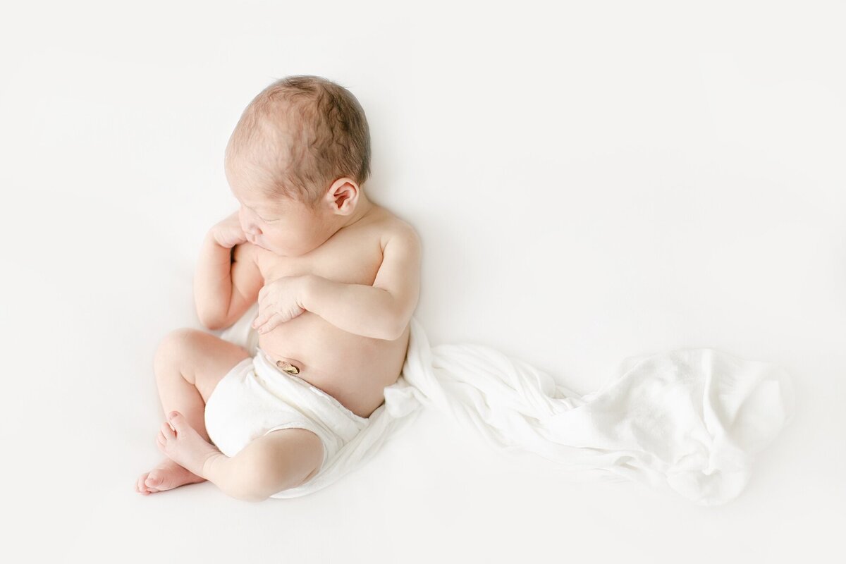 newborn baby laying on posing beanbag in all white
