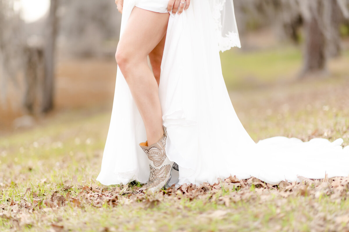 detail shot of brides cowboy boots as they peek through the slip of her wedding dress