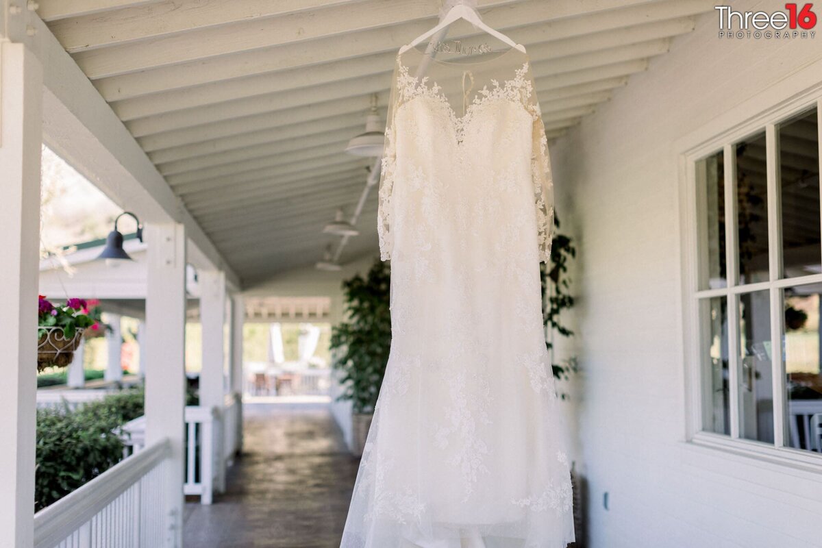 Bride's wedding gown hangs from the patio roof