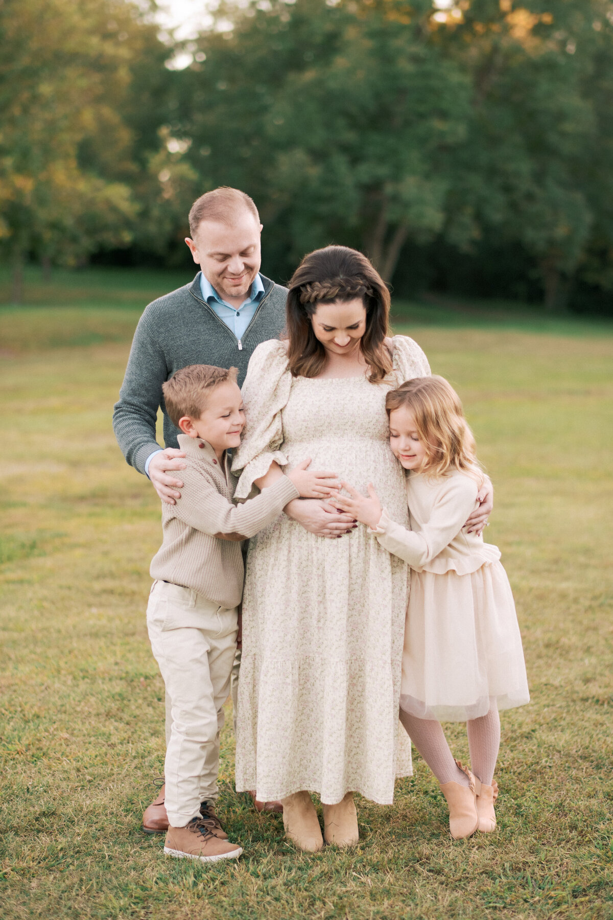 Older siblings snuggling the pregnant belly of their mom during a fall mini session at Oak View Park in Raleigh.  Image by Raleigh family photographer A.J. Dunlap Photography.