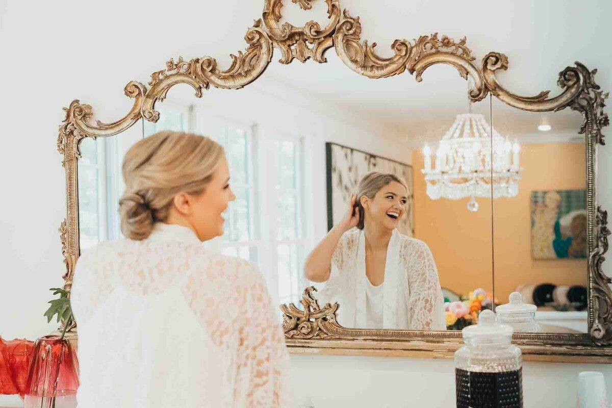 bride looks at her hair and makeup in vintage mirror at the Frenchie in Roundtop Texas for Ally's Photography