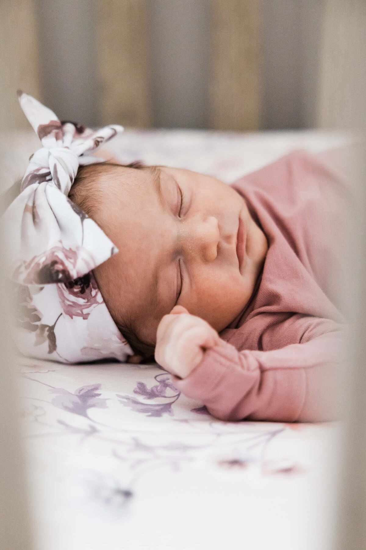 A newborn baby sleeps peacefully with a floral headband, showcasing the DIY newborn photos.
