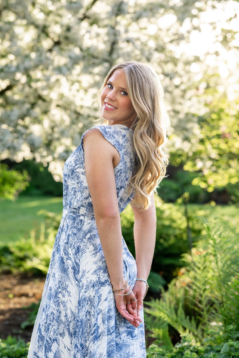 kirkland senior in blue dress under blossoming trees in spring