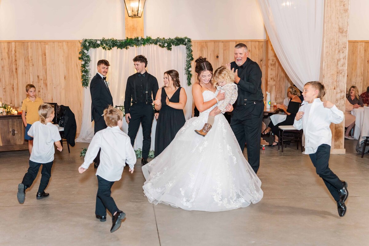 Kids run around the bride having fun as she laughs during her wedding reception