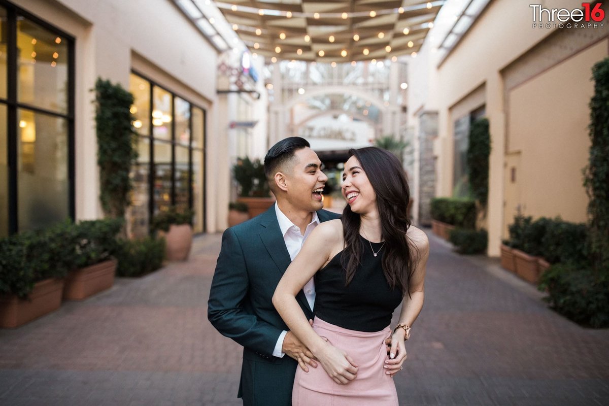 Engaged couple share a laugh during their engagement photo session
