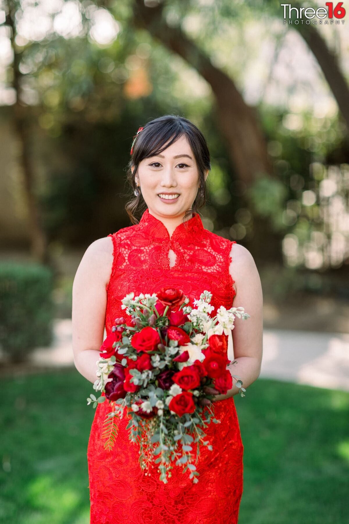 Bride posing in her stunning red gown holding her bouquet