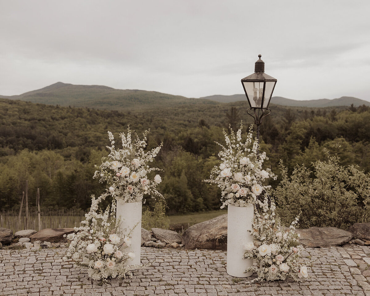 Large, elegant ceremony arrangements of white flowers at Chateau-Ste-Agnes. 
