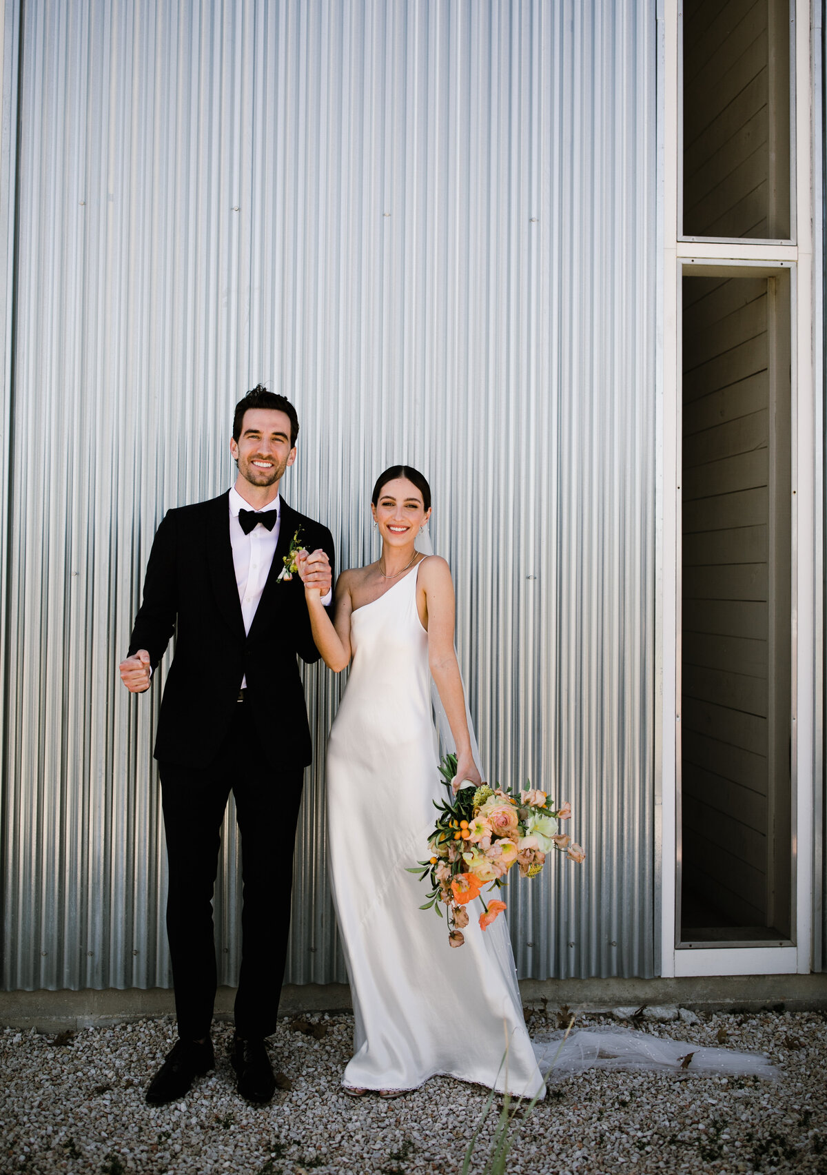 Bride and groom outside Prospect house, holding yellow and orange florals
