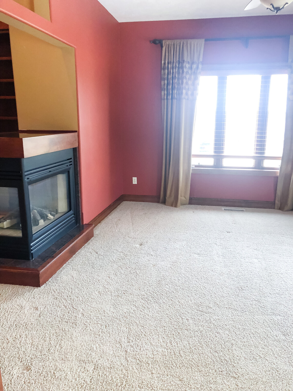 An empty room with old carpet and red walls