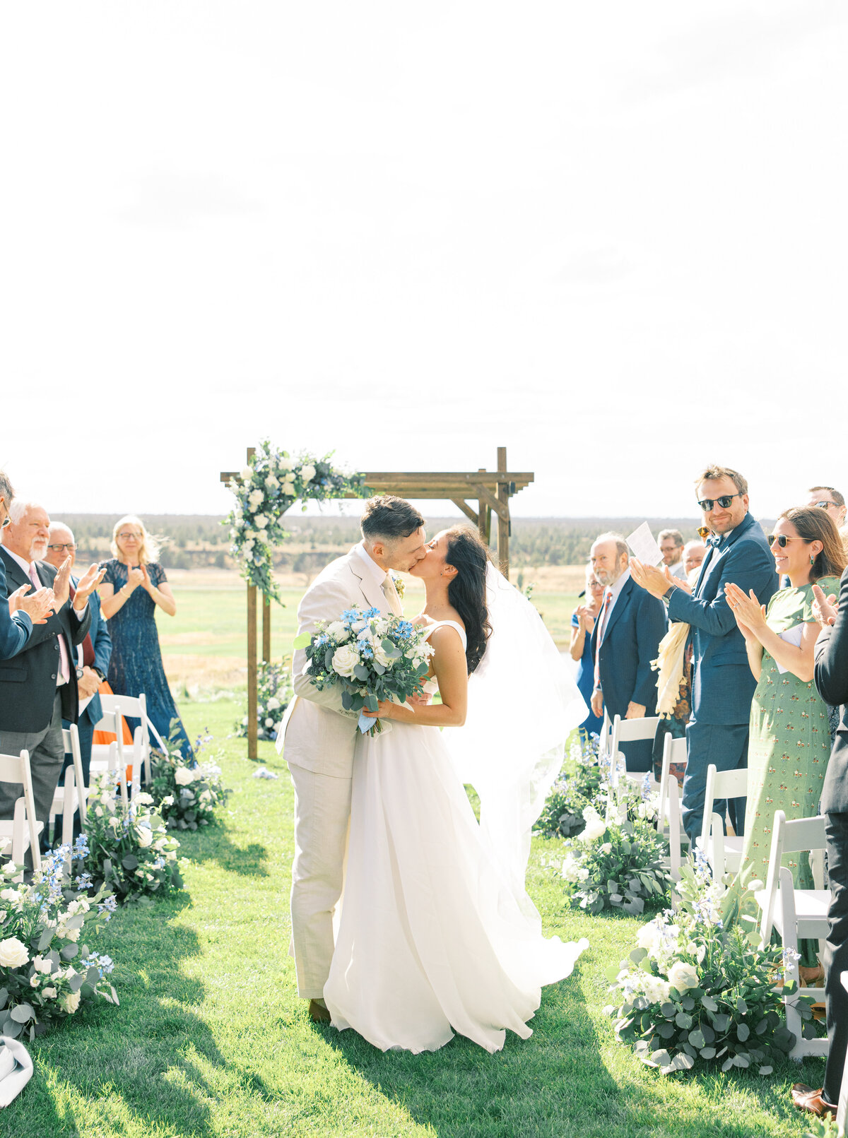 Bride and groom in front of chuppah with blue and white flowers along aisle at Brasada Ranch in Powell Butte Oregon