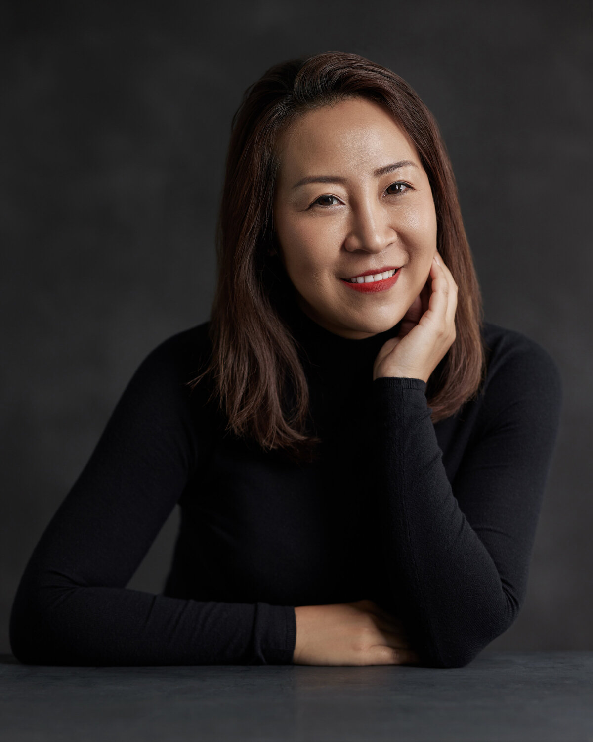 A woman smiling and resting her head in her hands