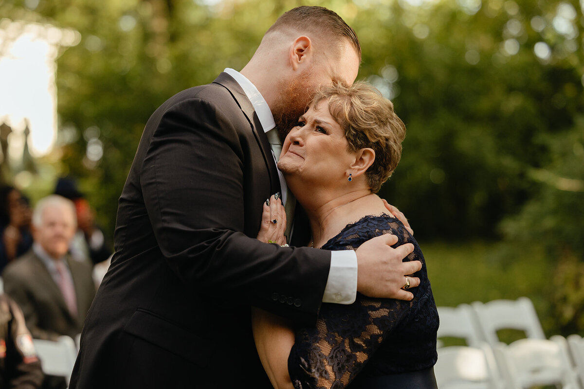 son hugging his mom as he walks down the aisle