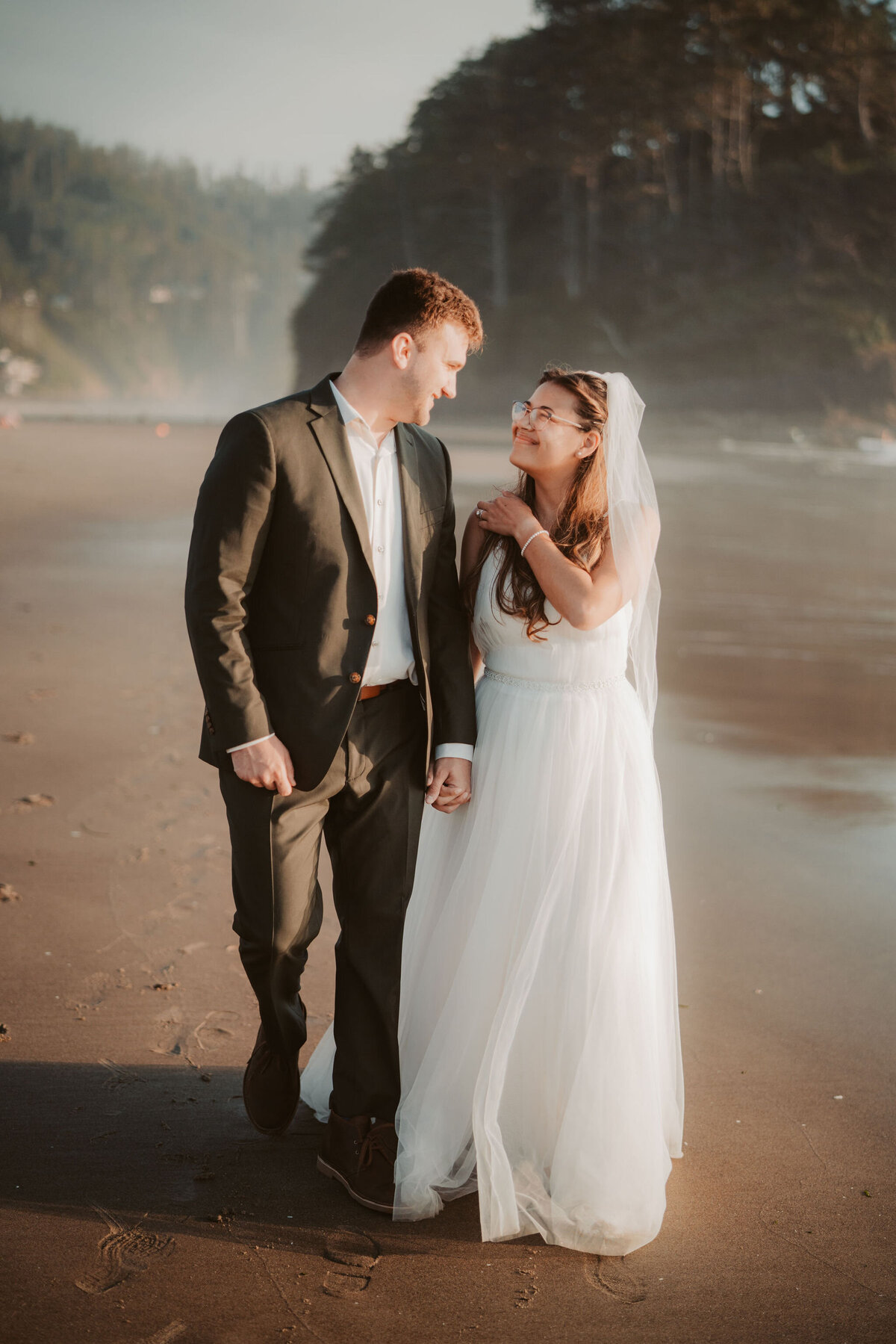 a bride and groom walking on an Oregon beach