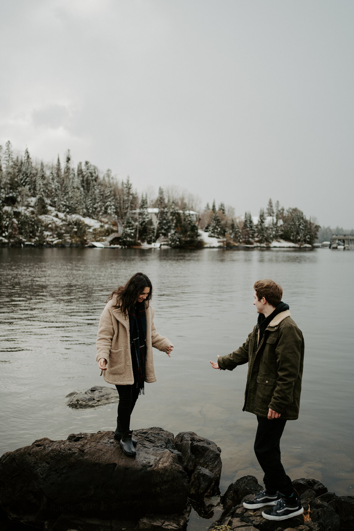 couple standing on rocks by lake