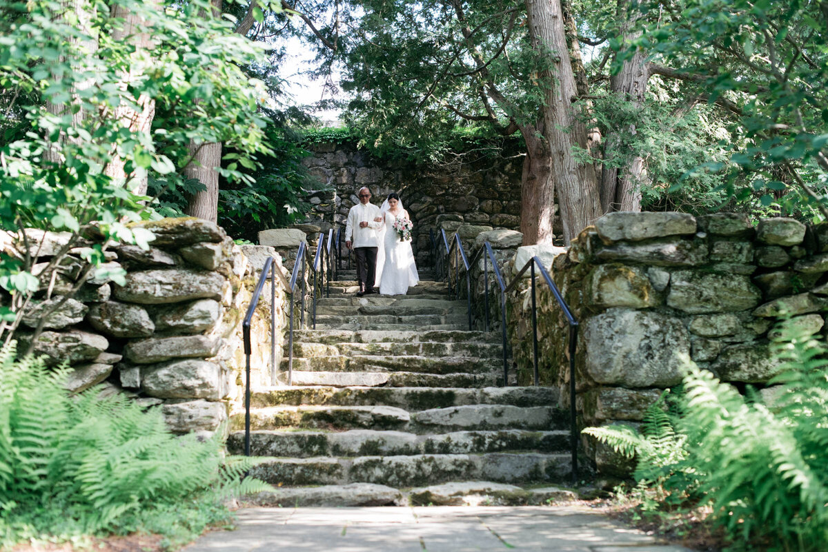 bride walking with father down stone stairs at the connors center