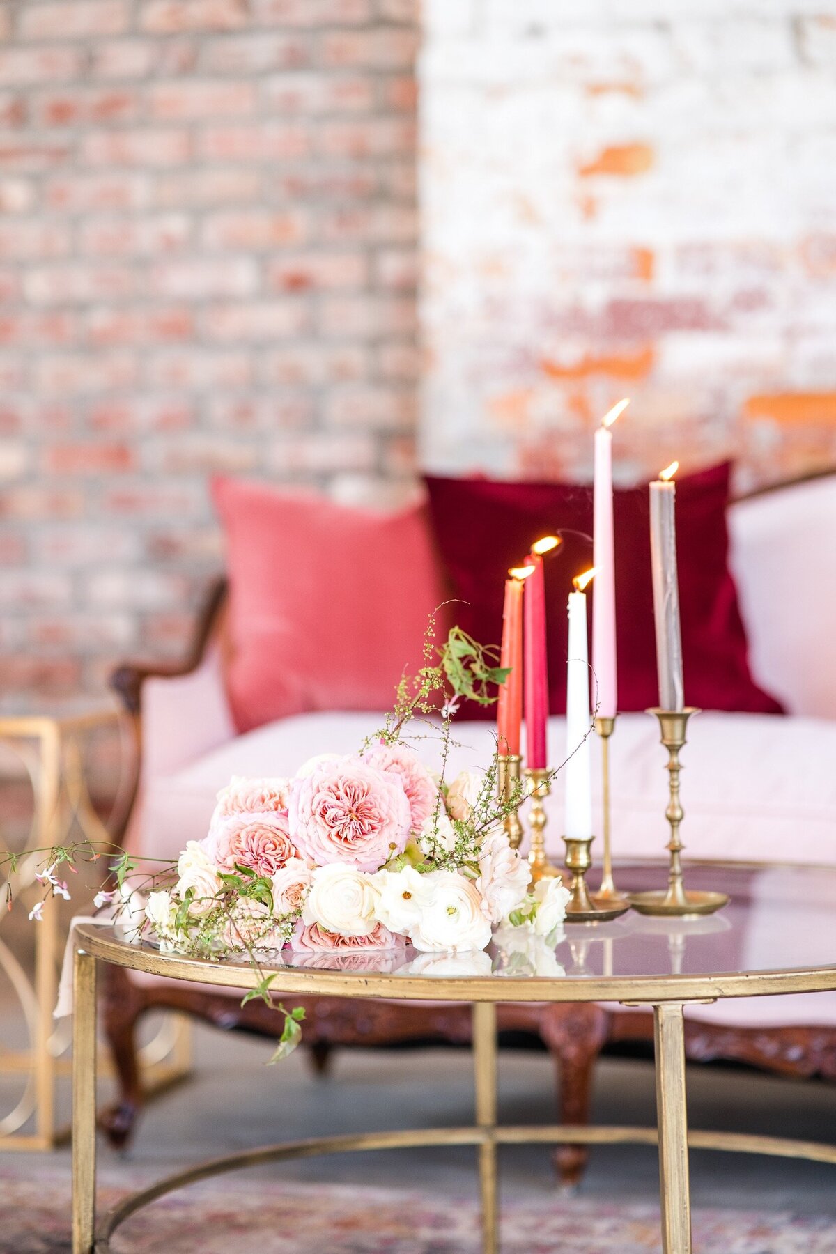 A photo of a spring bouquet on a table with tapered candles in front of a velvet couch at a venue near Charlotte, NC.