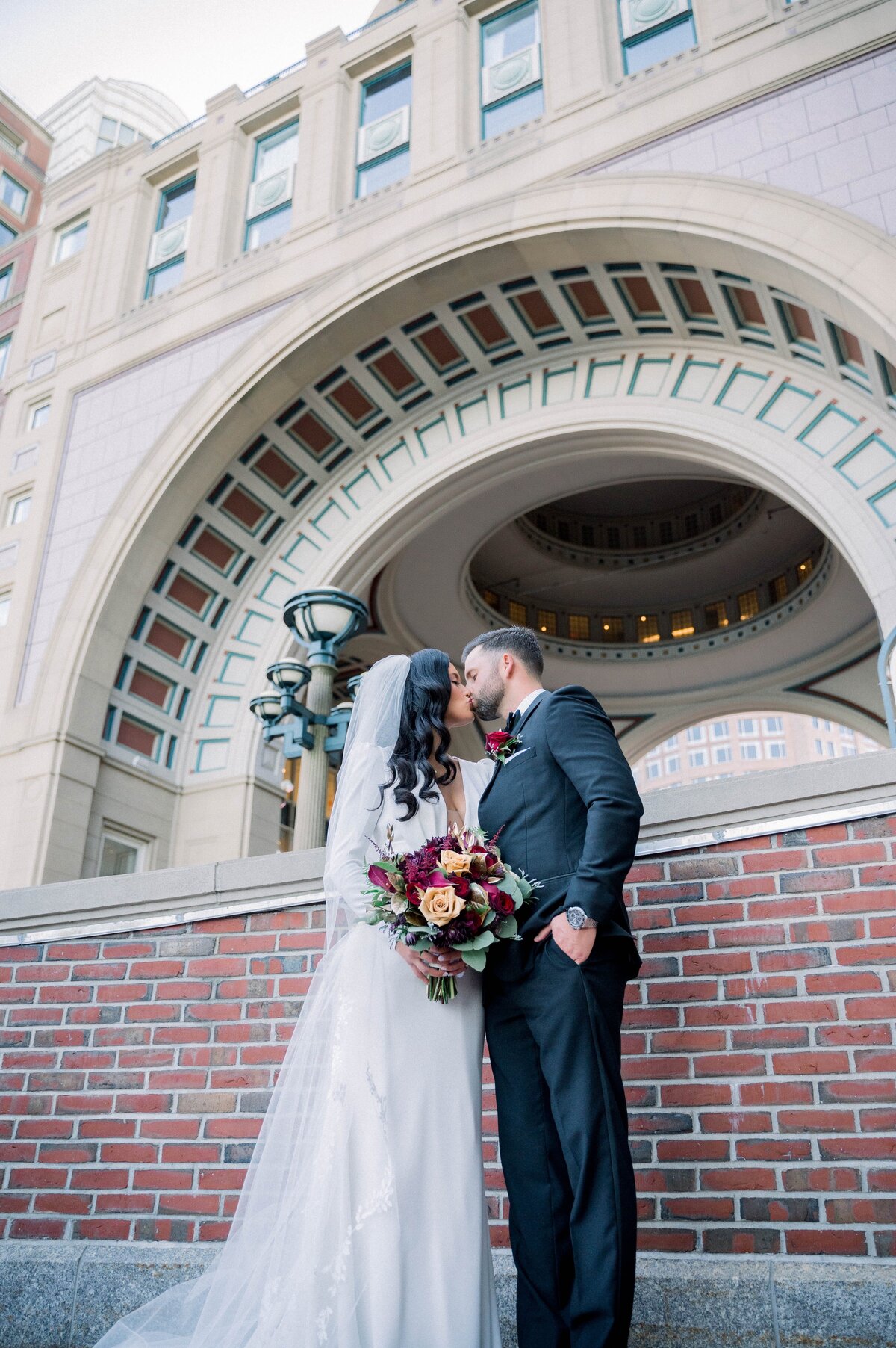 bride and groom kissing in front of the Boston Harbor Hotel