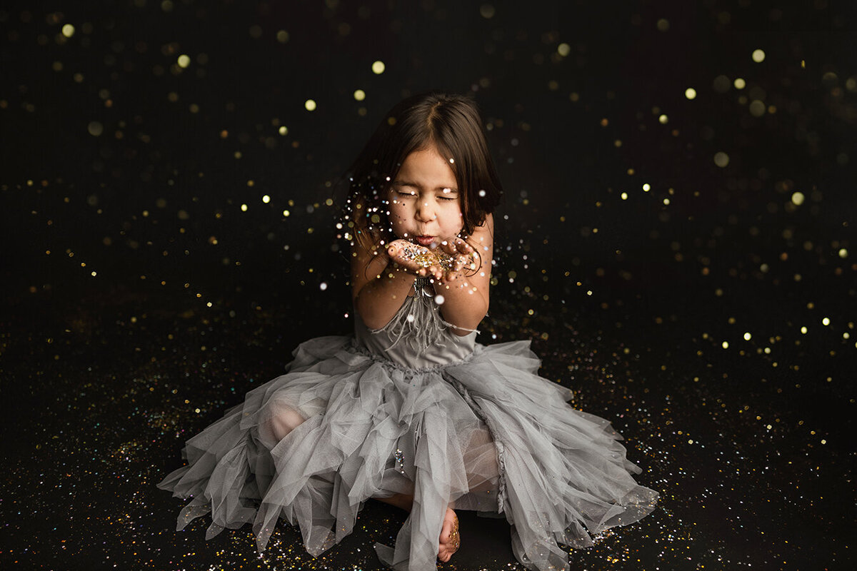 Beautiful photo of little girl blowing glitter