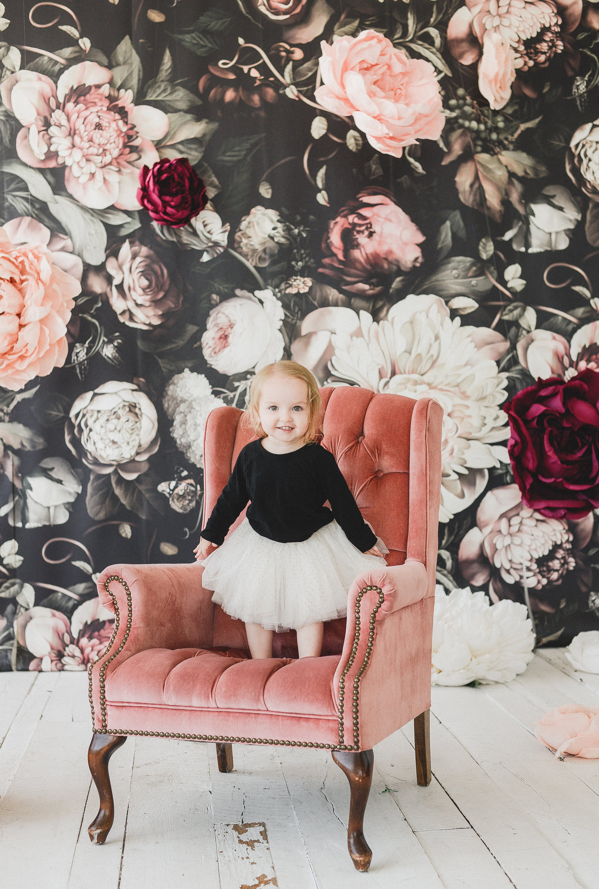 little girl standing on a blush pink chair