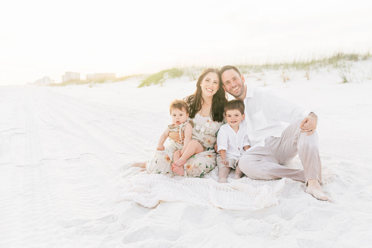 happy newborn family relaxing on a  bed in-home in Destin FL