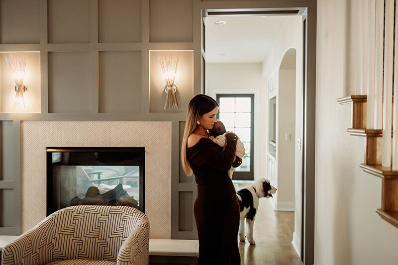 Mom walks newborn daughter to sleep while walking in the hallway during the family's newborn at home session in Denver
