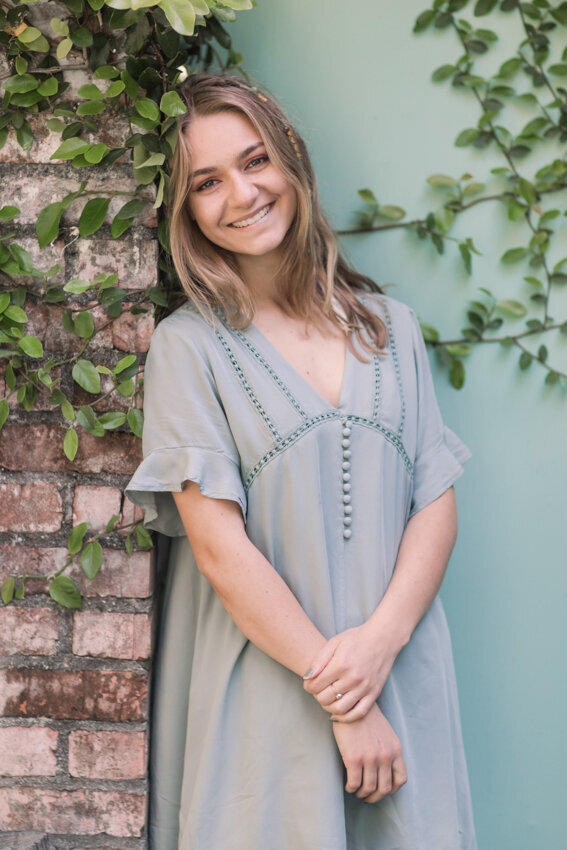 senior girl leaning against brick wall