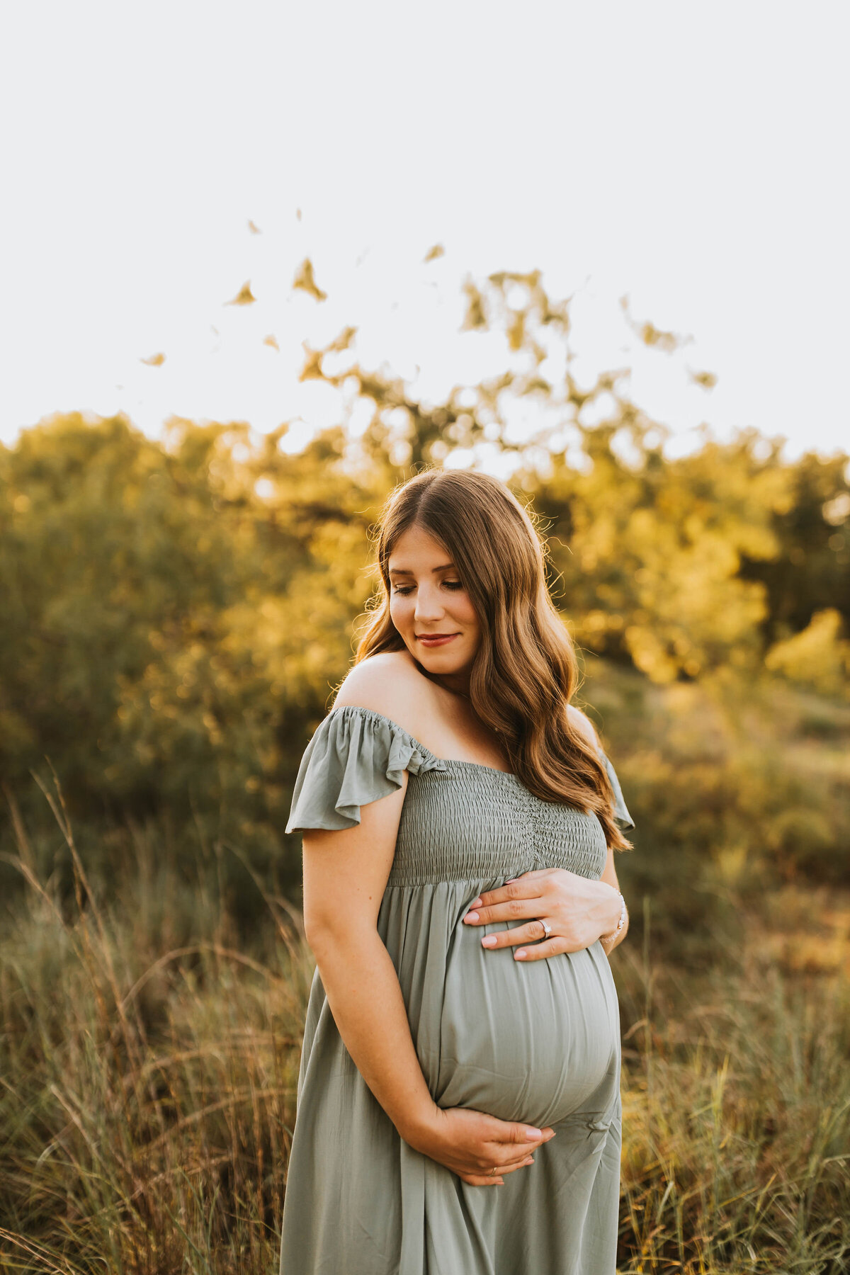 pregnant mom in a green field holding her belly and taking a deep  breath