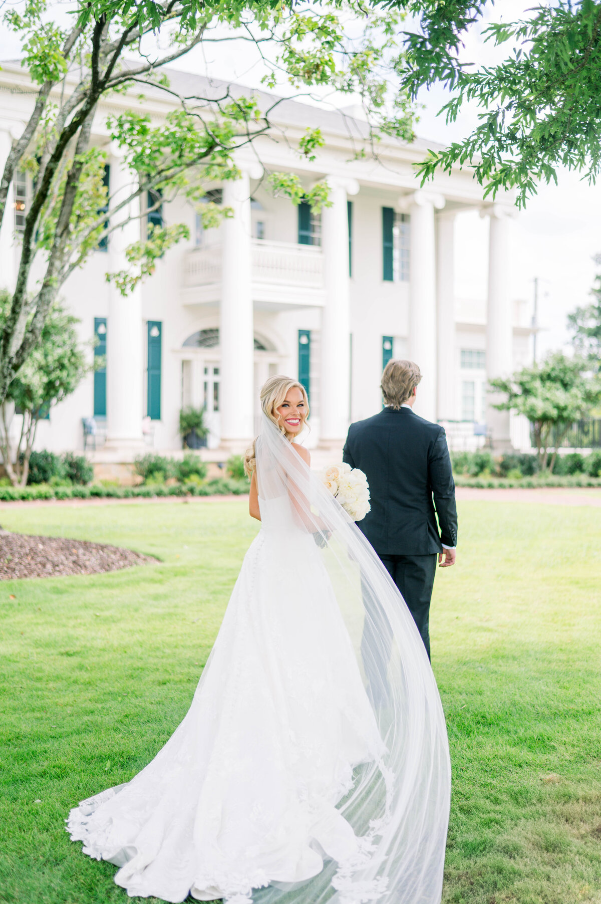 Newlyweds walking hand in hand across the lawn at the University Club, photographed in timeless, light-filled style