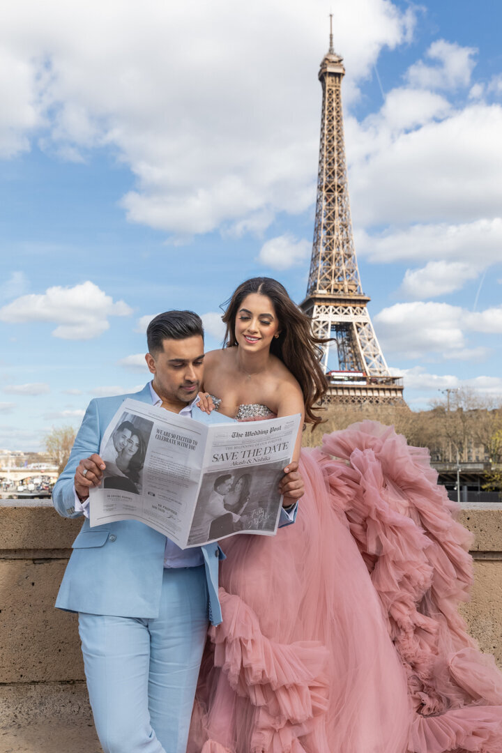 Paris engagement photo session, couple with Save the Date newspaper, Eiffel Tower backdrop, romantic announcement photoshoot