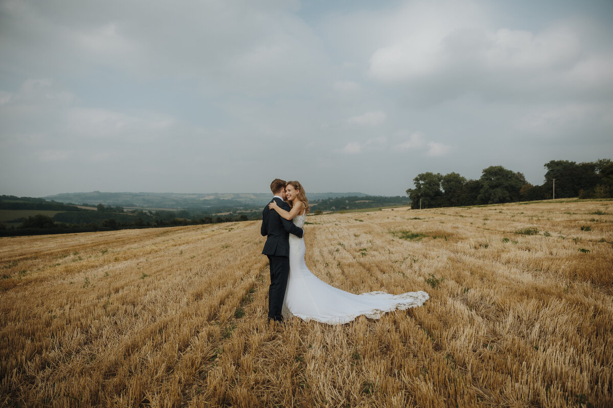 A bride and groom hugging in a barley field
