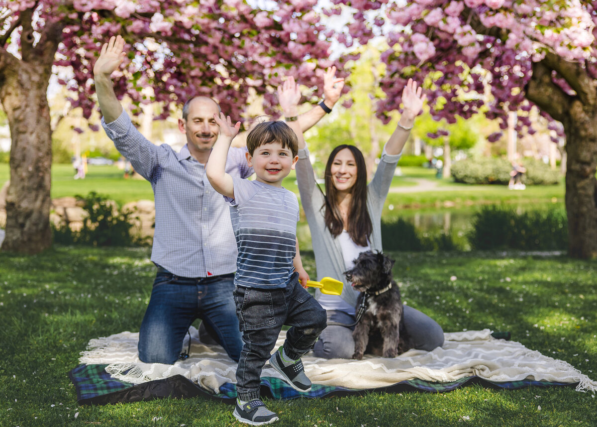 Lifestyle photo of family celebrating at an Essex County, New Jersey park. in front of cherry blossom trees.