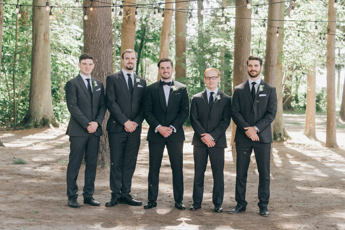Groomsmen posing for photos with the groom in black tie attire on a Summer wedding day at Wheatfield Estate