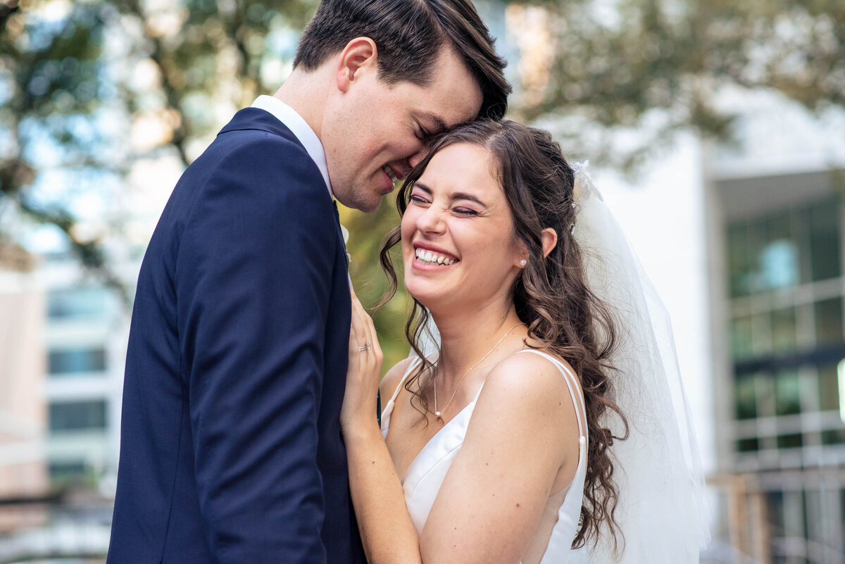 Up close photograph of a bride laughing as groom whispers in her ear outside the Mint Museum Uptown Mint_Museum_Wedding_Uptown_DeLong_Photography