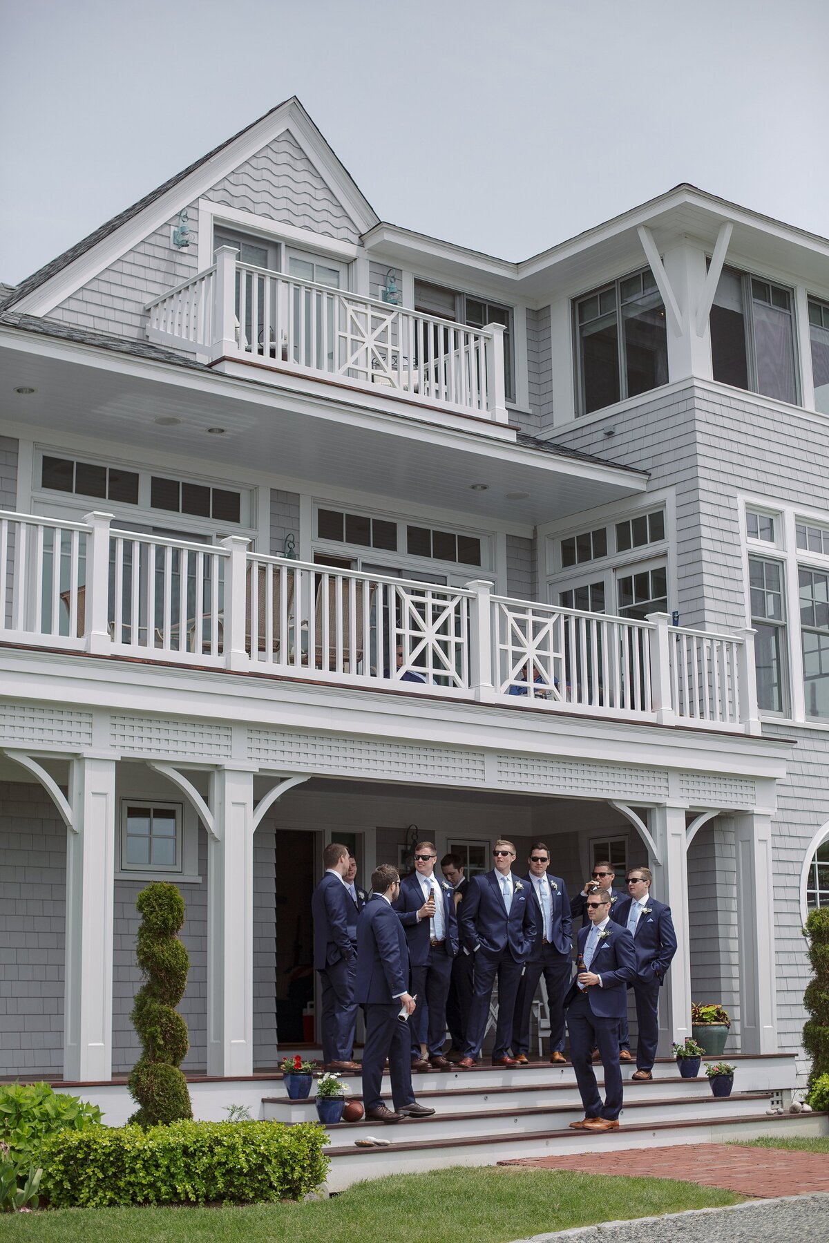 Groomsmen stand in front of coastal home before Newport wedding ceremony.