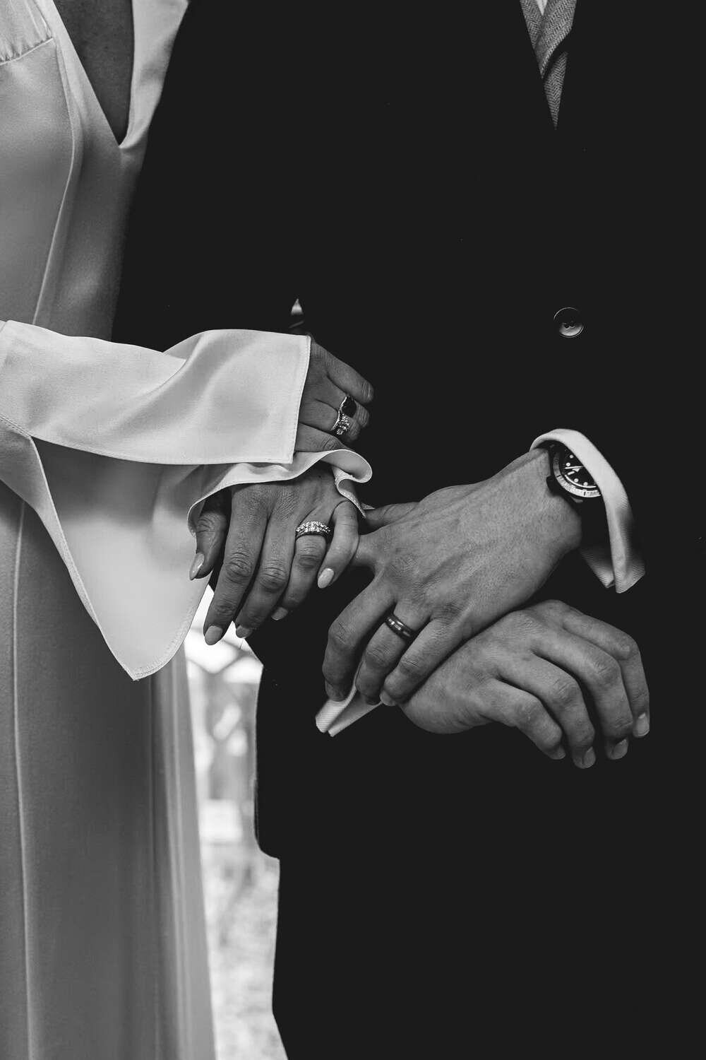 Interlocking arms of bride & groom displaying wedding rings