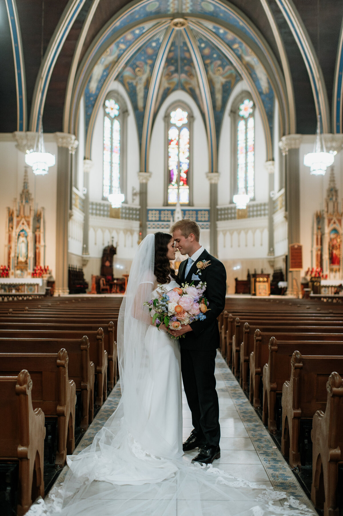 Bride standing alone in church aisle