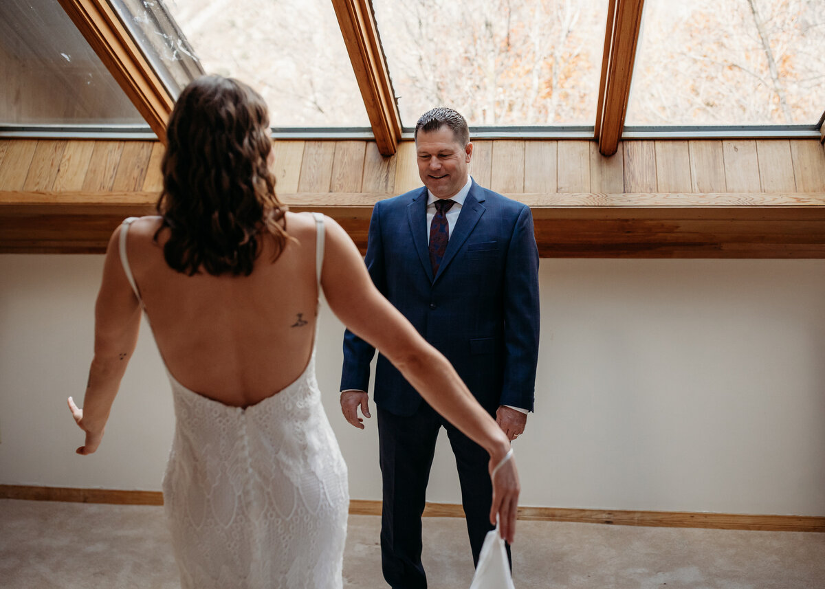 A bride reaching out to her father in a sunlit attic room, sharing a first look before the wedding