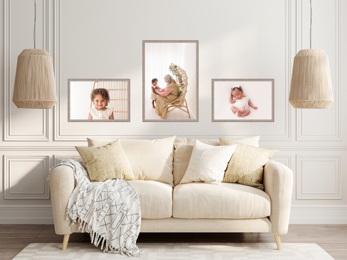 A cozy living room featuring an elegant off-white sofa with comfortable pillows and a throw blanket, with three framed photographs of a child hung above it, flanked by stylish pendant lamps.