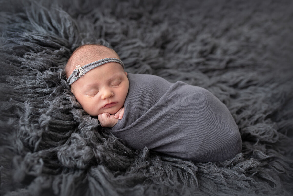 Wrapped Newborn in Grey Furry Background by Laura King