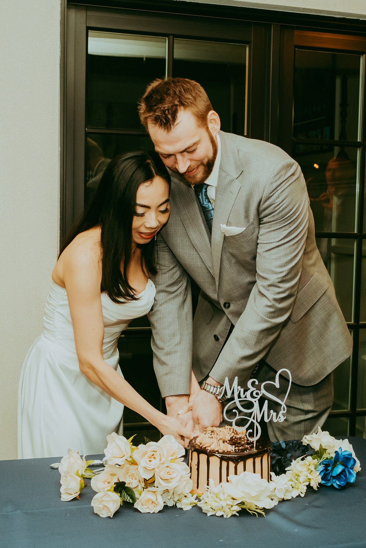 couple cuts wedding cake together